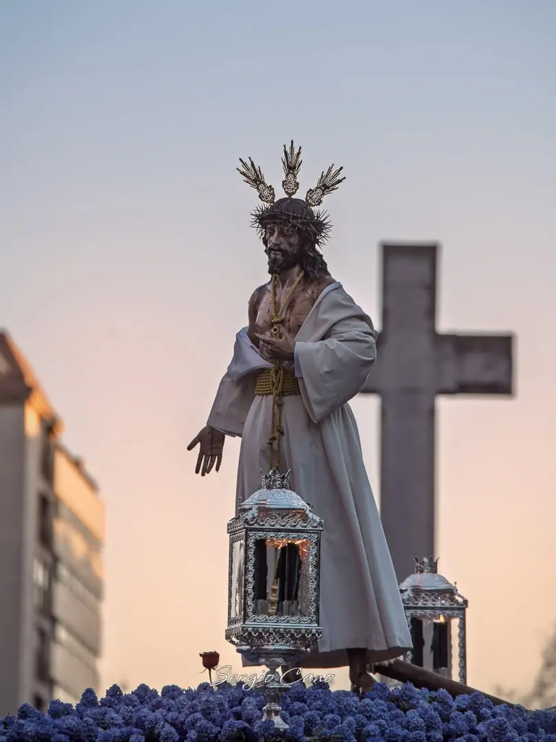 Nuestro Padre Jesús de la Lealtad Despojado durante la estación de penitencia, con una cruz al fondo